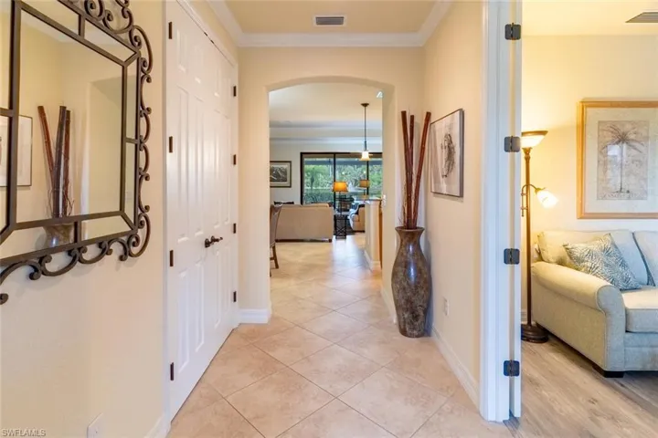 Hallway featuring baseboards, visible vents, and arched walkways