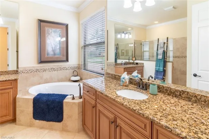 Bathroom featuring tile patterned floors, a sink, a bath, ornamental molding, and a walk in shower