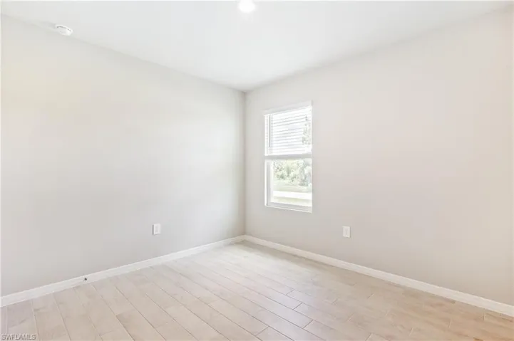 Spare room featuring light wood-style flooring and baseboards
