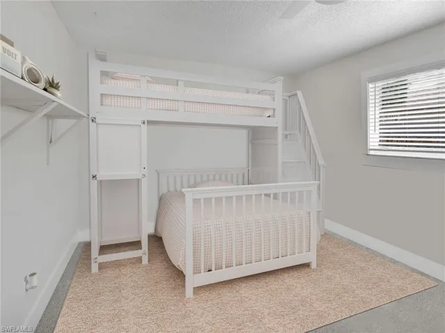 Bedroom featuring light colored carpet, a textured ceiling, and ceiling fan