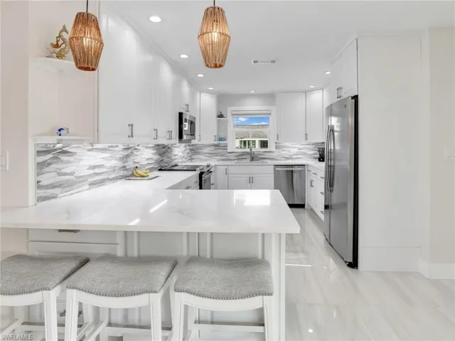 Kitchen featuring a breakfast bar area, appliances with stainless steel finishes, kitchen peninsula, and decorative light fixtures