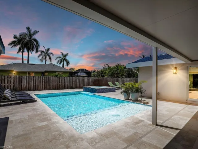 Pool at dusk featuring an in ground hot tub and a patio