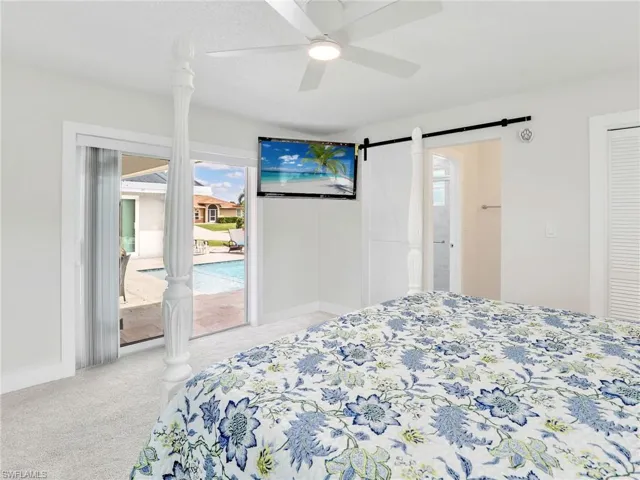 Bedroom featuring carpet floors, multiple windows, a barn door, and ceiling fan