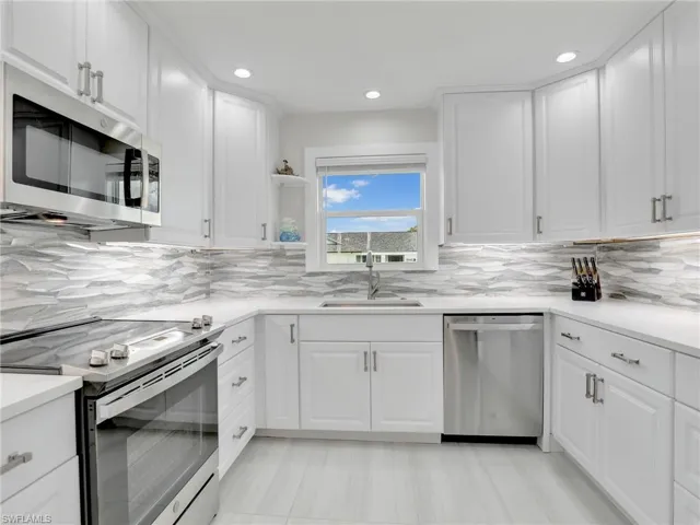 Kitchen featuring white cabinets, stainless steel appliances, tasteful backsplash, and sink