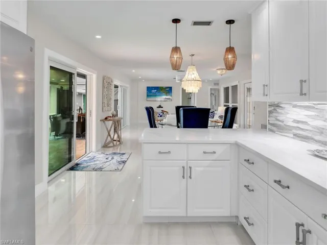 Kitchen featuring white cabinets, pendant lighting, light tile patterned floors, and kitchen peninsula