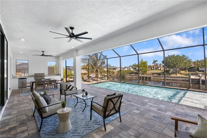 View of pool featuring an outdoor hangout area, a water view, glass enclosure, and a patio area