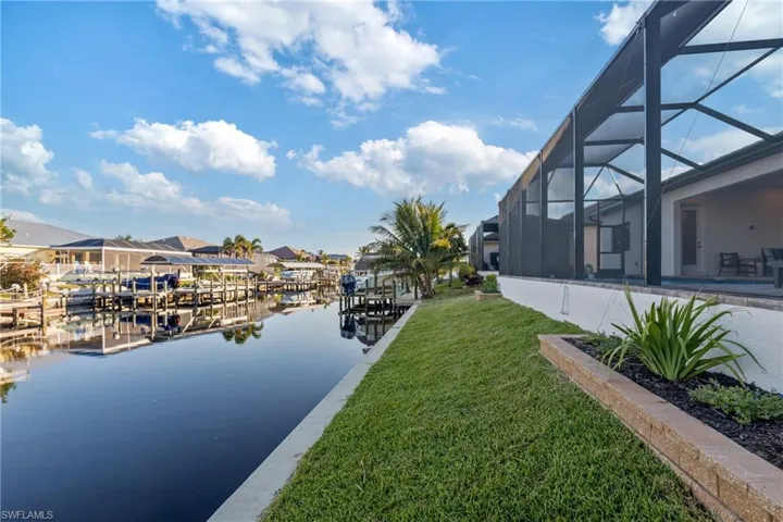 Dock area with a yard, a water view, and glass enclosure