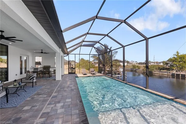 View of pool featuring a water view, ceiling fan, a lanai, and a patio area