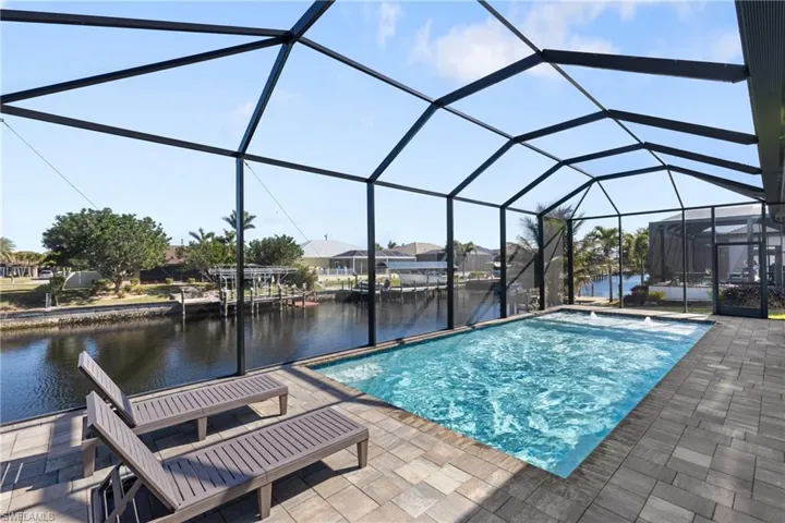 View of swimming pool featuring a patio, a water view, and glass enclosure