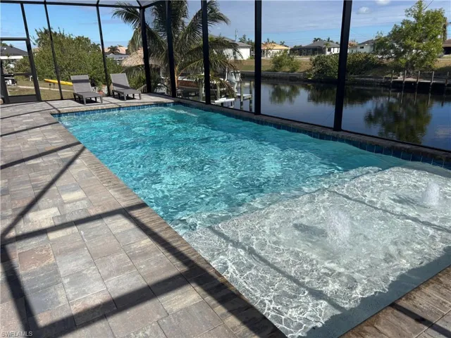 View of swimming pool featuring a patio, a water view, and a lanai