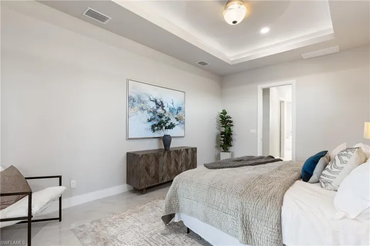 Bedroom featuring ceiling fan, a raised ceiling, and ensuite bath
