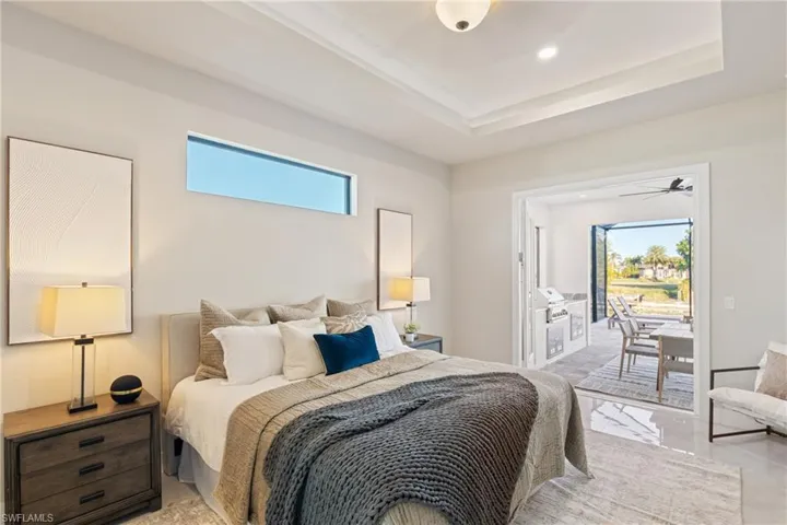 Bedroom featuring a tray ceiling, access to outside, and multiple windows