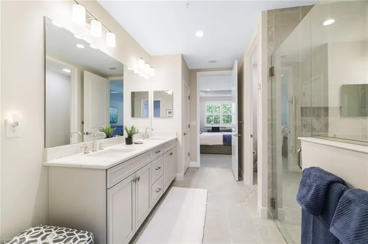 Ensuite bathroom with double vanity, a shower stall, recessed lighting, and light tile patterned flooring