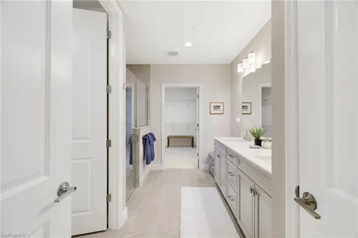 Bathroom with a walk in closet, shower, double vanity, recessed lighting, and light tile patterned flooring