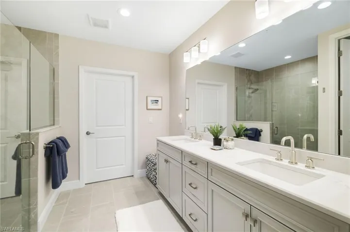 Bathroom with a shower stall, double vanity, recessed lighting, and light tile patterned floors