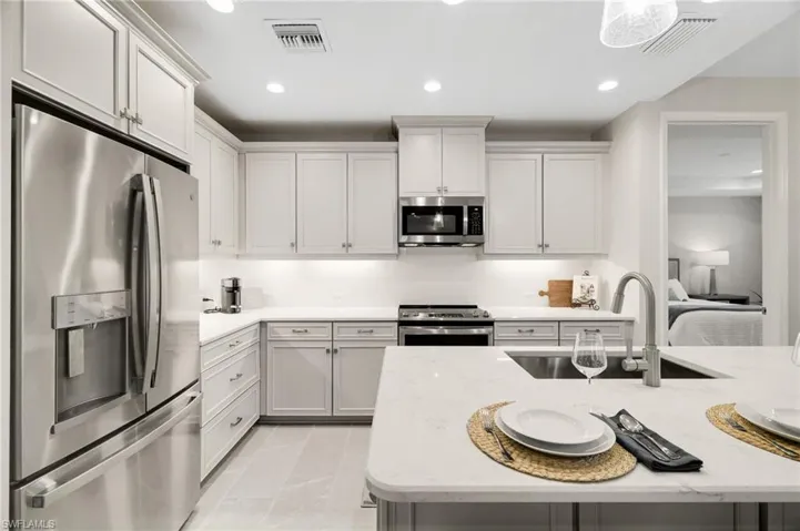 Kitchen featuring appliances with stainless steel finishes, recessed lighting, light stone counters, and white cabinets