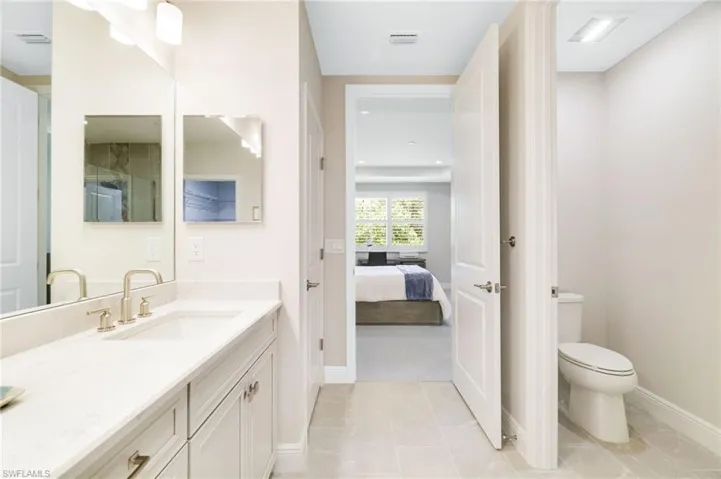 Ensuite bathroom, vanity, and light tile patterned floors