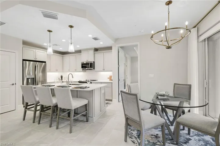 Kitchen with a breakfast bar area, a kitchen island with sink, recessed lighting, stainless steel appliances, and white cabinets