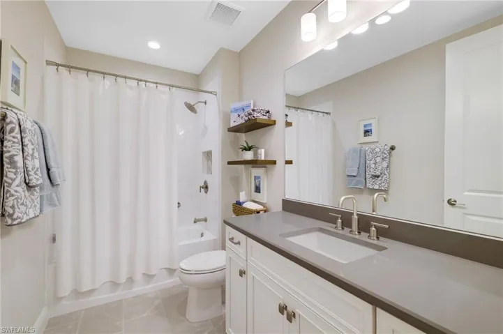 Full bath with vanity, shower / bath combination with curtain, and light tile patterned floors