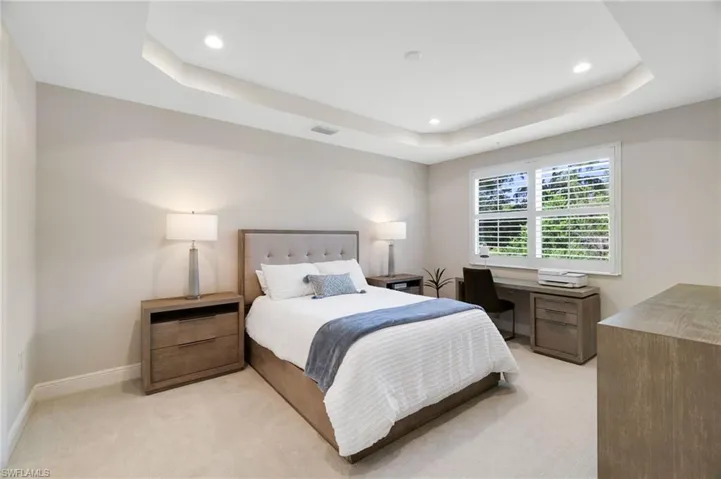 Bedroom with light colored carpet, recessed lighting, and a raised ceiling