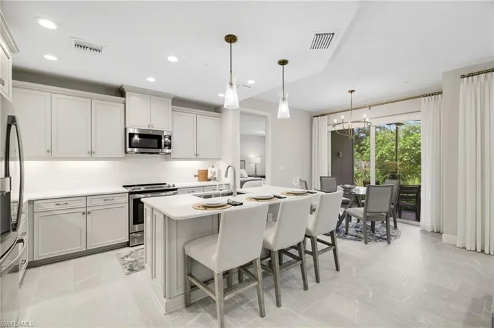 Kitchen featuring stainless steel appliances, a kitchen bar, an island with sink, recessed lighting, and pendant lighting