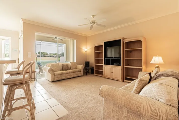 Living room featuring carpet, ceiling fan, and ornamental molding