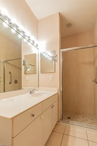 Bathroom with tile patterned floors, a shower with door, and vanity