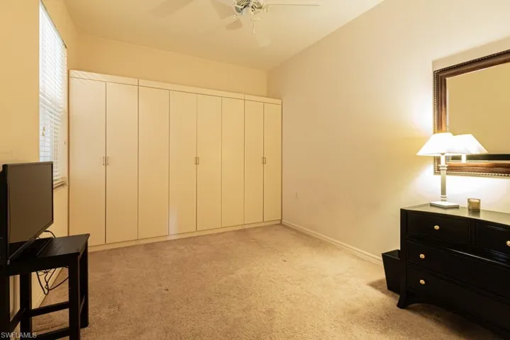 Bedroom with a closet, light colored carpet, and ceiling fan
