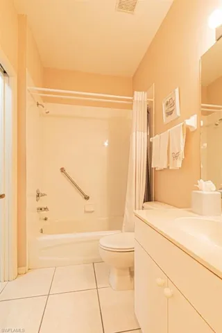 Full bathroom with vanity, tile patterned flooring, shower / bathtub combination with curtain, and toilet