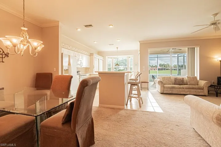 Carpeted dining room featuring ceiling fan with notable chandelier and crown molding