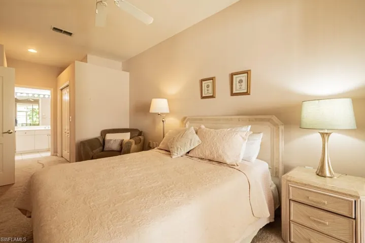 Bedroom featuring ensuite bathroom, ceiling fan, and light carpet