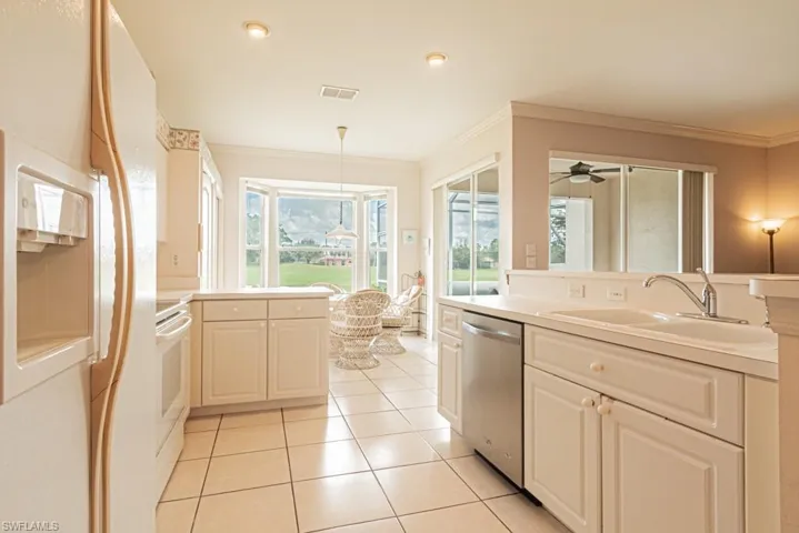 Kitchen featuring ceiling fan, sink, hanging light fixtures, white appliances, and ornamental molding