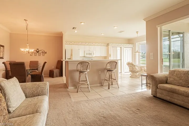 Living room featuring a notable chandelier, crown molding, and light carpet