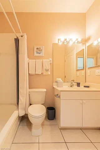 Full bathroom with tile patterned flooring, shower / bath combo, toilet, and vanity