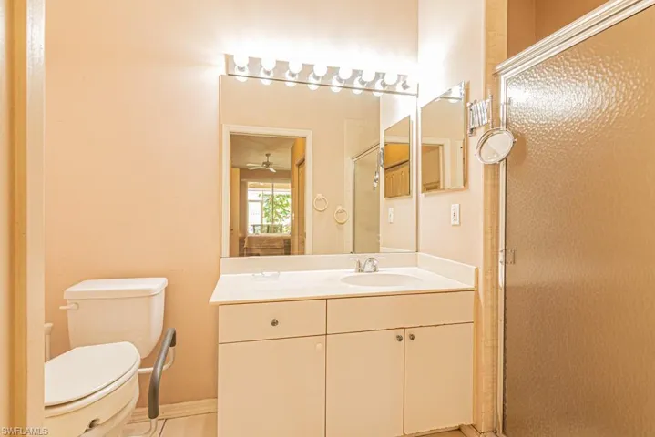 Bathroom with an enclosed shower, vanity, ceiling fan, tile patterned flooring, and toilet