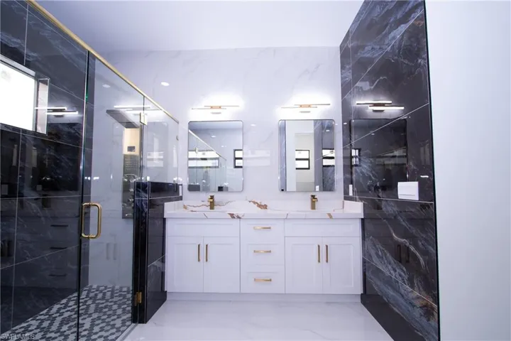 Bathroom featuring vanity, a shower with door, and tile walls