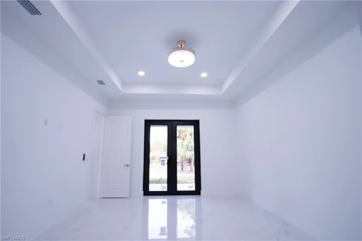 Spare room featuring a raised ceiling and french doors