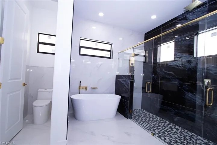 Bathroom featuring a wealth of natural light, shower with separate bathtub, and toilet