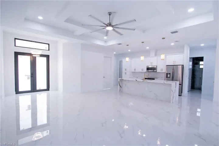 Living room with sink, a tray ceiling, french doors, and ceiling fan