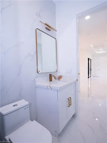 Bathroom featuring vanity, toilet, and tile walls