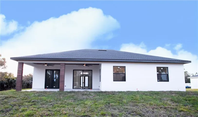 Rear view of house with a lawn and ceiling fan