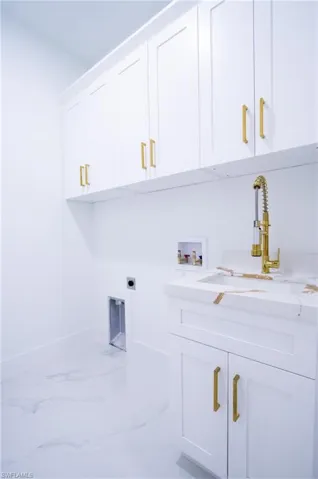 Clothes washing area with electric dryer hookup, sink, hookup for a washing machine, and cabinets