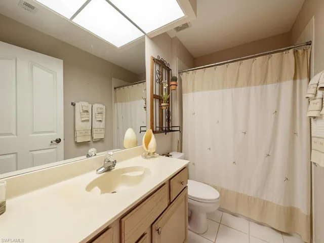 Full bathroom with a shower with shower curtain, vanity, and light tile patterned floors