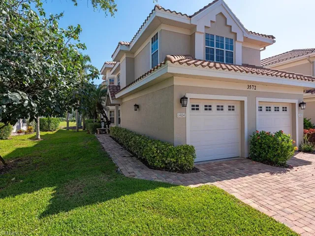 View of front of house featuring a front yard, stucco siding, decorative driveway, and a tile roof
