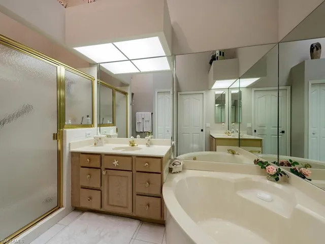 Full bath with a stall shower, two vanities, a garden tub, and light tile patterned floors