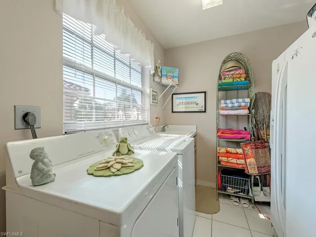 Laundry area featuring light tile patterned floors and washing machine and clothes dryer