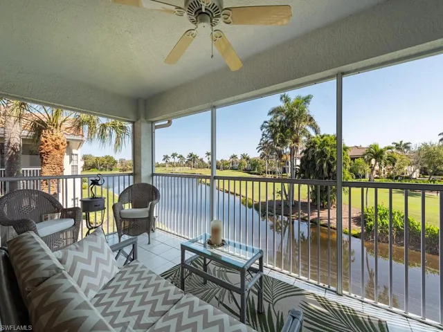 Sunroom / solarium with a water view, a textured wall, and tile patterned flooring
