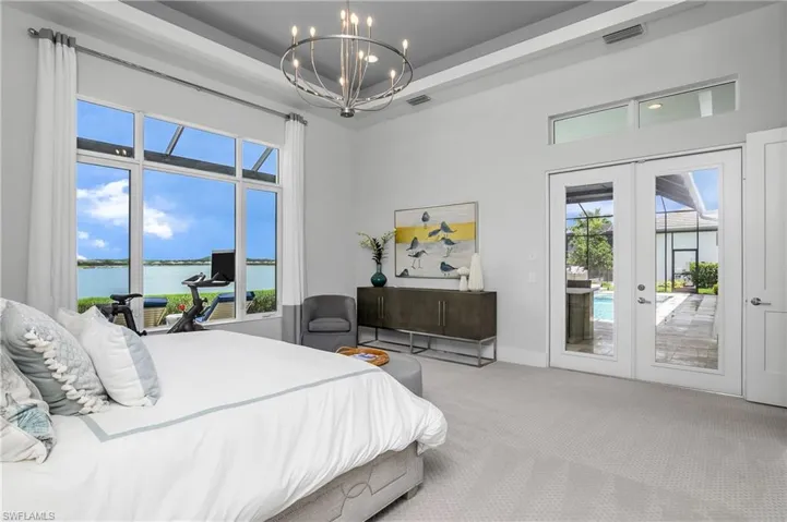 Bedroom featuring a water view, multiple windows, light colored carpet, and access to outside