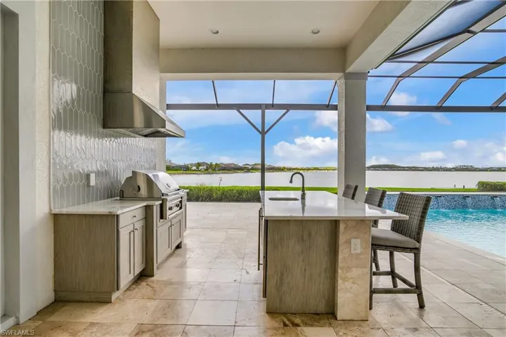 View of patio with a lanai, a water view, area for grilling, and sink