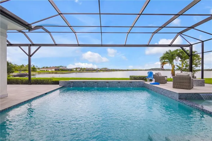 View of swimming pool with a water view, glass enclosure, a patio, and pool water feature